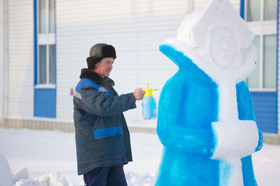 The master paints the figure of a snow woman on the street on a winter day. production of new year