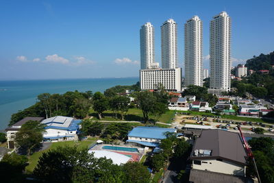 Modern city by sea against blue sky