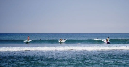 People in sea against clear sky