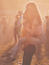 Teenage girl giving friend piggyback ride while standing outdoors