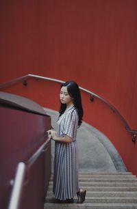 Side view of young woman standing on staircase