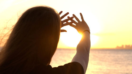 Close-up of woman against sea during sunset