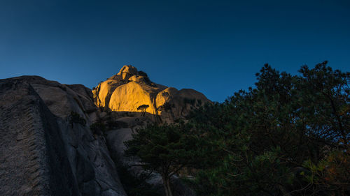 Low angle view of rock formation against clear blue sky