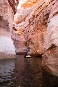 Man paddleboarding on lake amidst rock formations