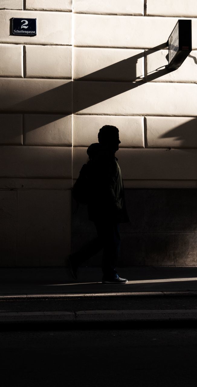 REAR VIEW OF MAN WALKING ON SUBWAY PLATFORM