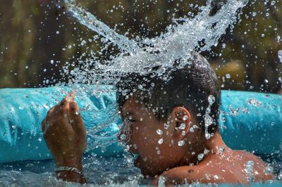 Portrait of man splashing in swimming pool