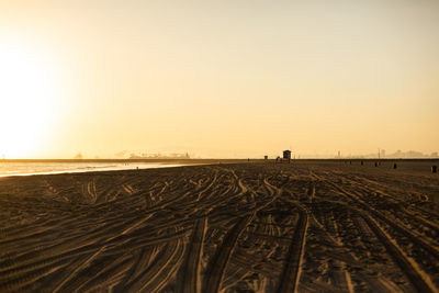 Railroad tracks on field against clear sky during sunset