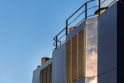 Low angle view of industry against clear blue sky