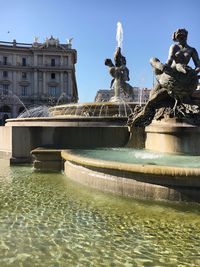 Fountain in city against sky