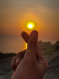 Person hand on sun during sunset