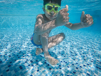 Portrait of shirtless boy swimming underwater in pool 