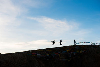 Low angle view of silhouette women on hill against sky