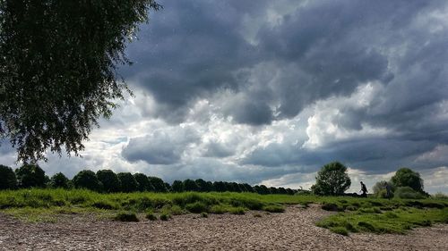 Scenic view of field against storm clouds