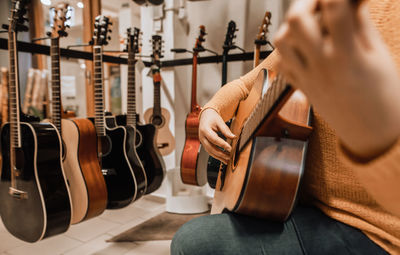 Midsection of woman playing guitar at store