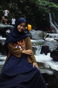 Young woman standing by waterfall in winter