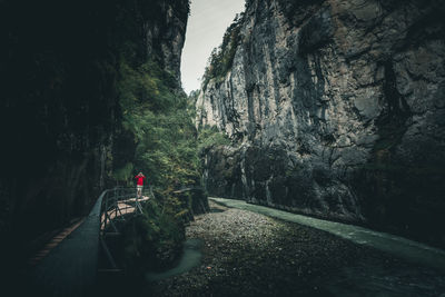 Mature man photographing on footbridge against rock formation