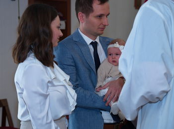 Parents holding their baby girl in a church ready for christening