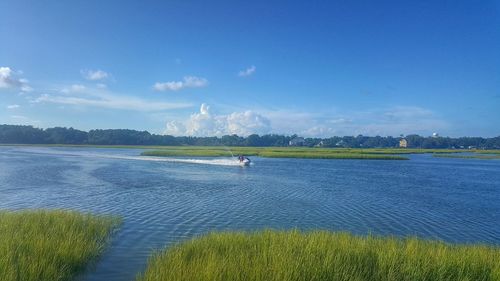 People jet boating on lake against sky