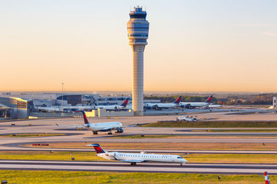 Airplane on airport runway against sky during sunset