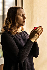 A young woman holds a newly blown candle in her hand.