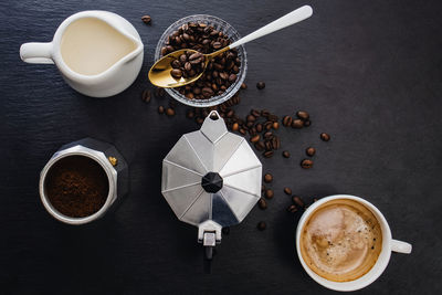 Still life with moka pot, coffee beans, milk, sugar and fresh hot espresso in a cup. 
