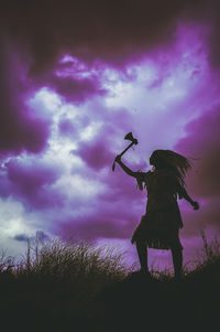 Rear view of silhouette girl standing on field against sky at sunset