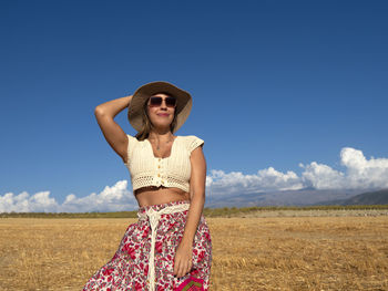 Young woman standing on field against clear blue sky