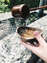 Cropped hands holding bowl on drinking water