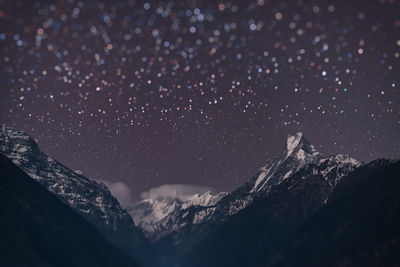 Scenic view of snowcapped mountains against sky at night