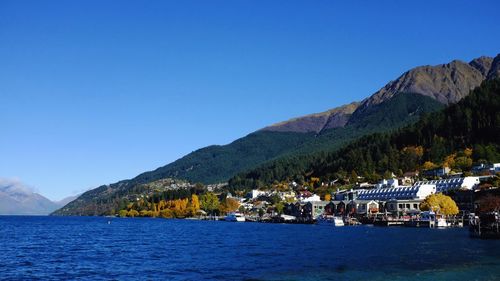 Scenic view of sea and mountains against clear blue sky