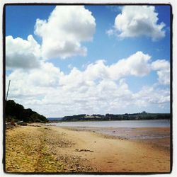 Scenic view of beach against cloudy sky