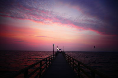 Pier on beach during sunset