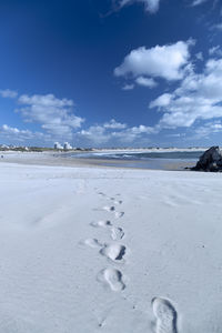 Footprints on snow covered land against sky