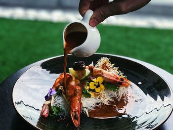 Cropped hand of person pouring drink in food