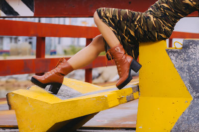 Low section of woman leaning on built structure