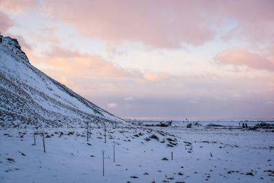 Snow covered land against sky during sunset