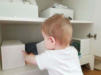 Rear view of baby playing with white boxes at home