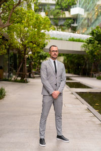 Portrait of young man standing against trees