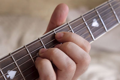 Man playing guitar chord. strumming acoustic guitar. male fingers and fretboard closeup. guitar neck