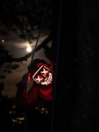 Person wearing mask against trees at night