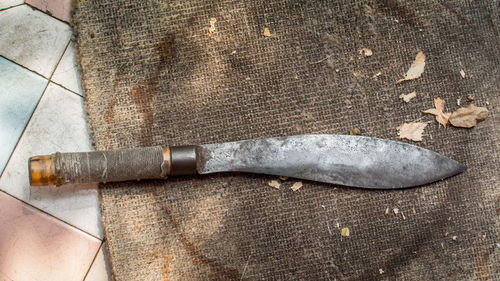High angle view of old knife on jute fabric over tile floor
