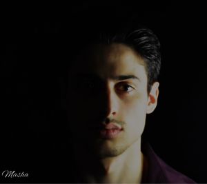 Portrait of young man against black background