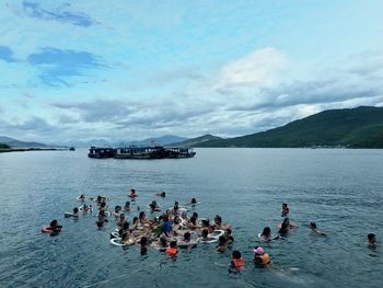 People swimming in sea against sky