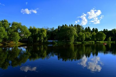 Reflection of trees in lake against blue sky