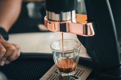 Close-up of hand pouring coffee in glass