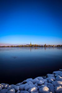 Scenic view of lake against clear blue sky