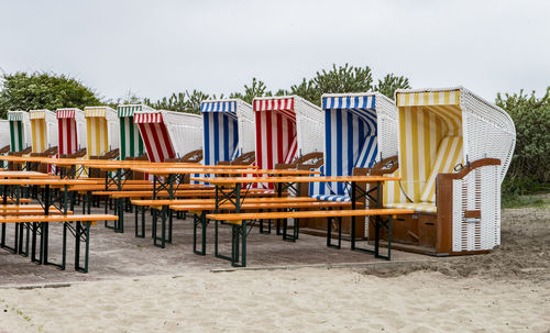 Chairs on table at beach against sky