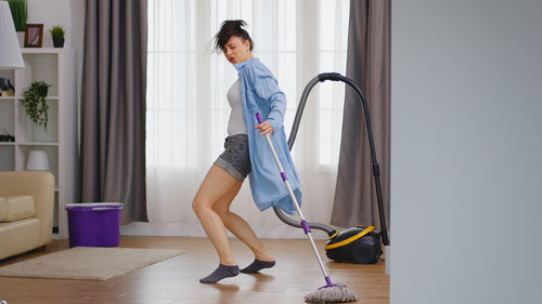 Cheerful woman cleaning house floor