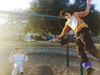 Siblings enjoying swing at playground