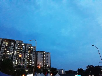 Low angle view of illuminated city against blue sky